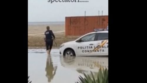 Imagini cu o maşină a Poliţiei Locale Constanţa, blocată în nisip, pe plajă / Un agent umblă desculţ, iar altul şi-a pus saci de gunoi peste încălţăminte, încercând să scoată maşina