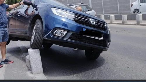 FOTO Echilibristică în Capitală cu Dacia Logan: Un șofer a ”parcat” pe un stâlp de beton de pe marginea străzii