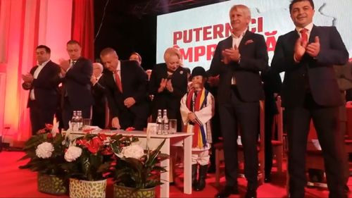 VIDEO: Un copil adus la ședința PSD Alba, pus să aplaude pe scenă de către premierul Viorica Dăncilă când i se strigă numele șefei PSD. Băiatul apare și în pozele de campanie de la Țebea