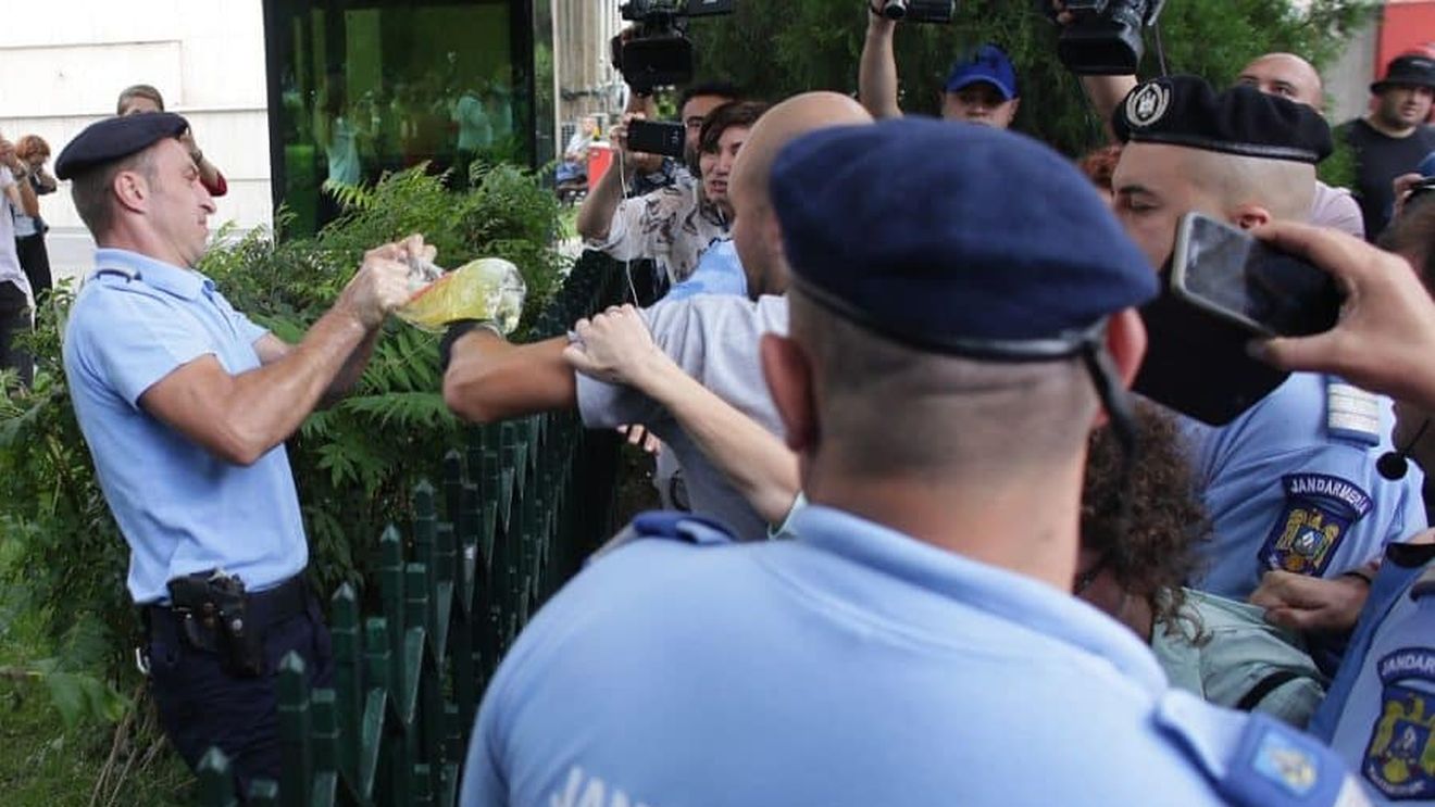 Imagini VIDEO: Momentul în care un jandarm i-a smuls bidonul cu benzină protestatarului Cristian Dide, care se legase de gardul Guvernului. Jandarmii au tăiat gardul