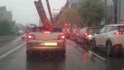 VIDEO Filmat în timp ce transportă țevi, cu o decapotabilă, pe ploaie