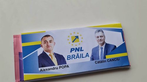 Ciocolate Milka cu reclamă electorală PNL, distribuite la Brăila. Pe ambalaj apar fotografiile liderilor PNL din județ