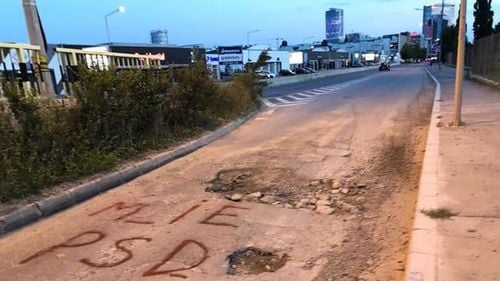 Soluție extremă pentru repararea șoselelor pline de gropi: Oamenii au scris pe asfalt ”M_IE PSD” în speranța acoperirii craterelor
