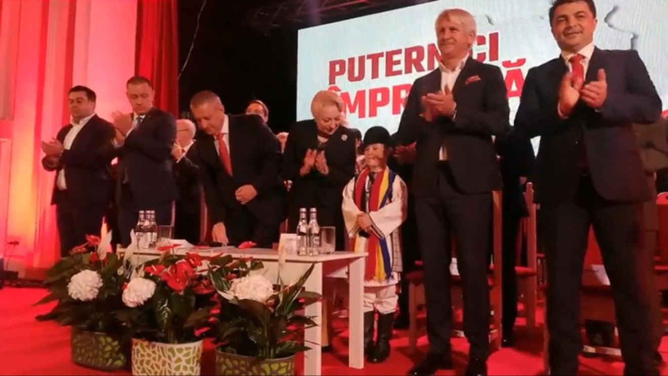 VIDEO: Un copil adus la ședința PSD Alba, pus să aplaude pe scenă de către premierul Viorica Dăncilă când i se strigă numele șefei PSD. Băiatul apare și în pozele de campanie de la Țebea