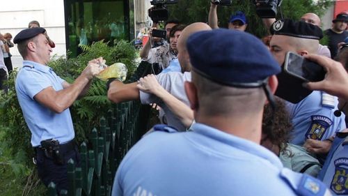 Imagini VIDEO: Momentul în care un jandarm i-a smuls bidonul cu benzină protestatarului Cristian Dide, care se legase de gardul Guvernului. Jandarmii au tăiat gardul