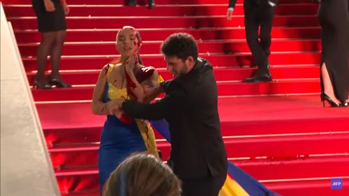 O femeie îmbrăcată în culorile drapelului Ucrainei s-a acoperit cu sânge fals, pe covorul roşu de la Cannes